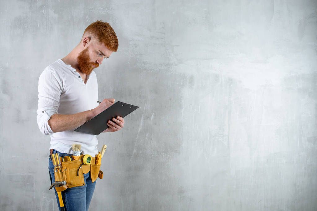 бородатый брутальный архитектор, инженер, пишущий на цифровой планшетной копии шпата на бетонной стене
 - Фото, изображение