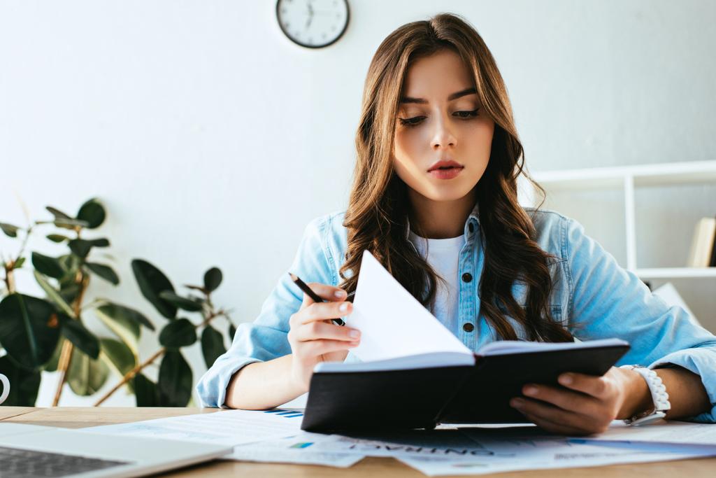 Portret van jonge zakenvrouw met laptop op werk met papieren en laptop in kantoor - Foto, afbeelding