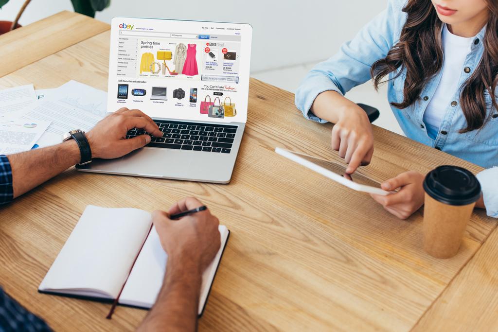 частичный взгляд коллег по бизнесу с ноутбуком с логотипом ebay и планшетом, принимающих участие в вебинаре в офисе
 - Фото, изображение