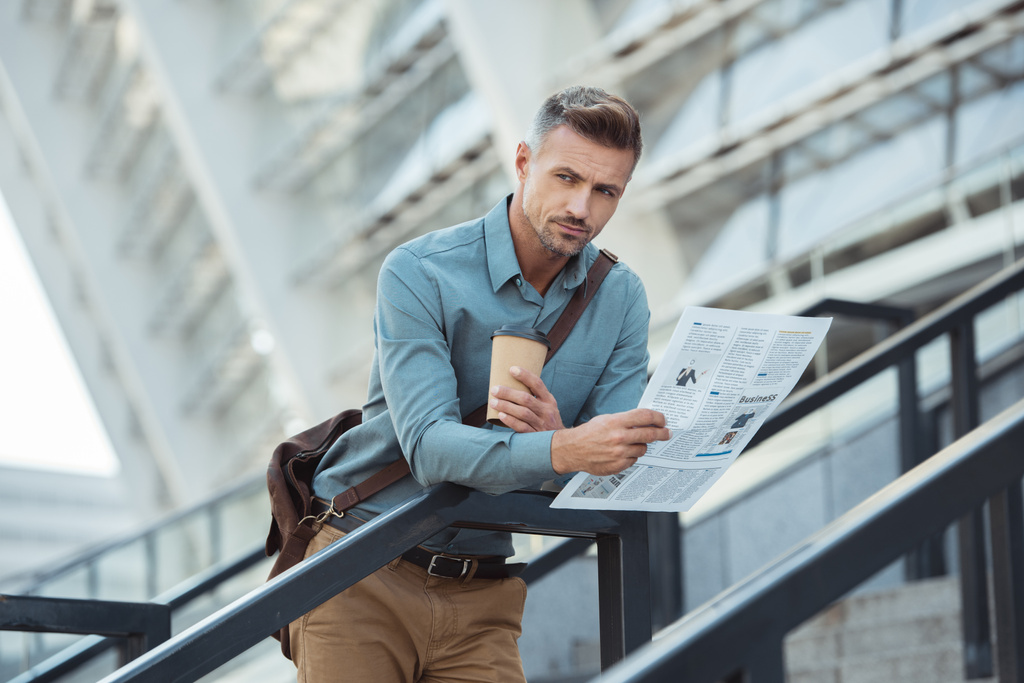 pohledný středního věku muž drží noviny stoje a káva s sebou na schody - Fotografie, Obrázek