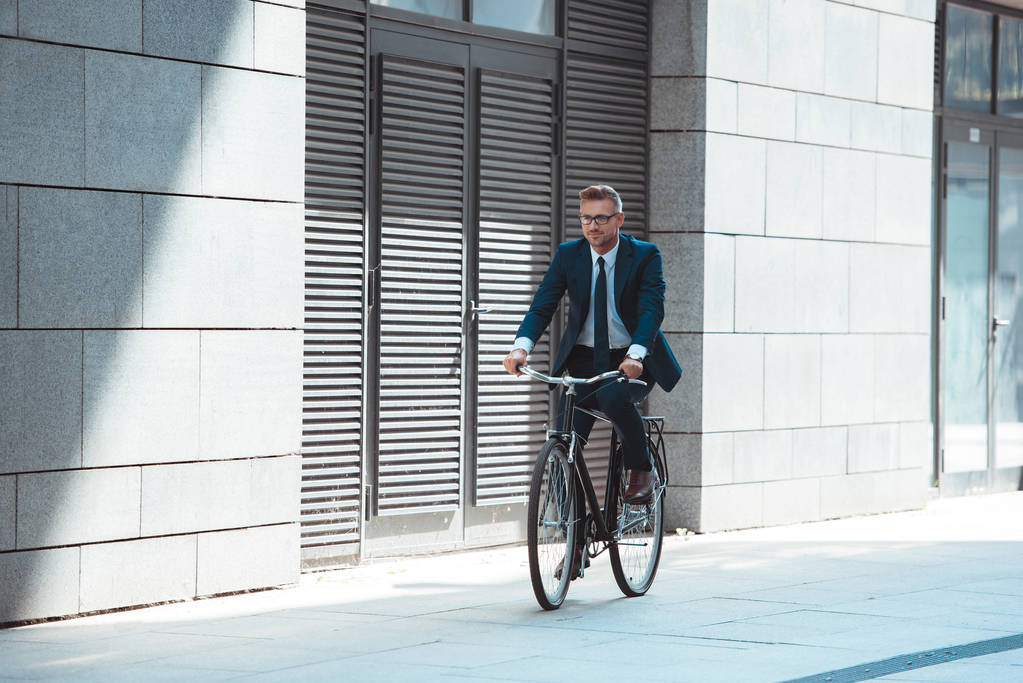 Geschäftsmann mittleren Alters in Anzug und Brille mit Fahrrad auf der Straße - Foto, Bild