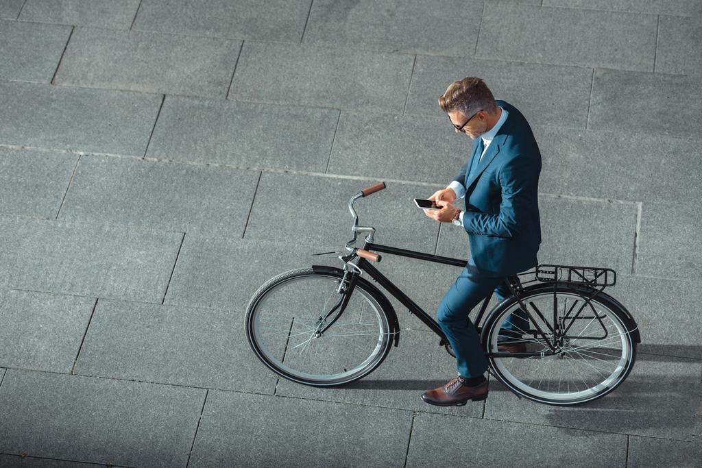 işadamı ile bisiklet Caddesi üzerinde duran smartphone kullanarak resmi aşınmaya yüksek açılı görünüş  - Fotoğraf, Görsel