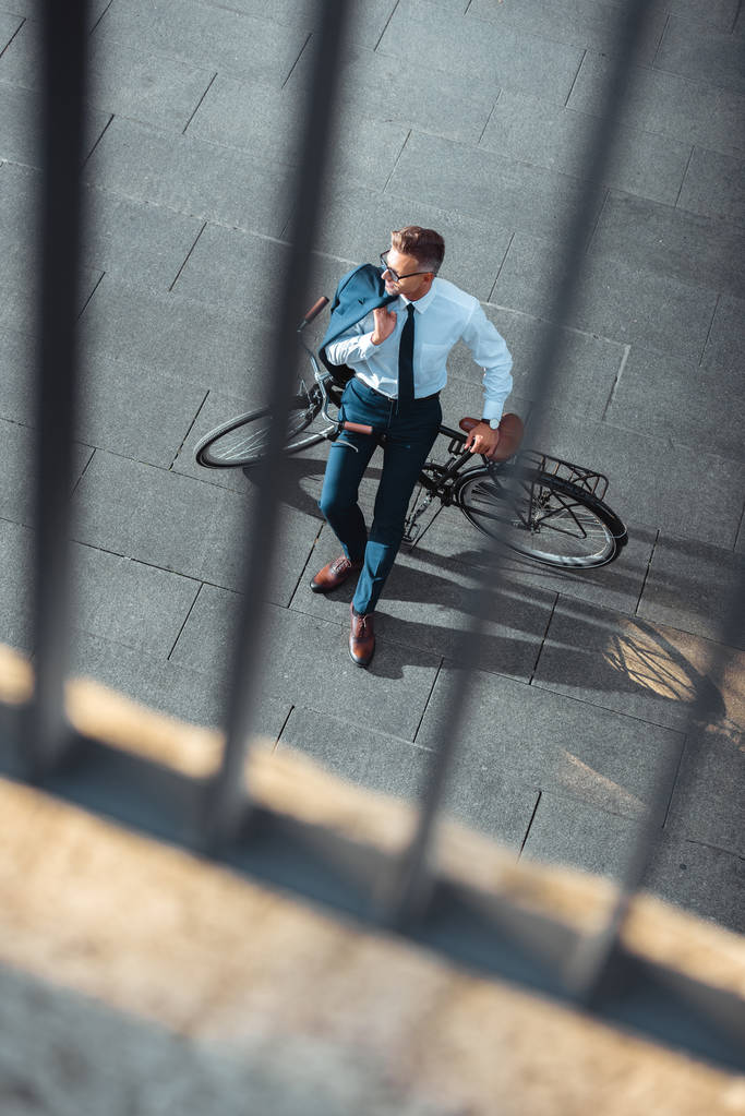 selective focus of businessman holding suit jacket and sitting on bike - Photo, Image