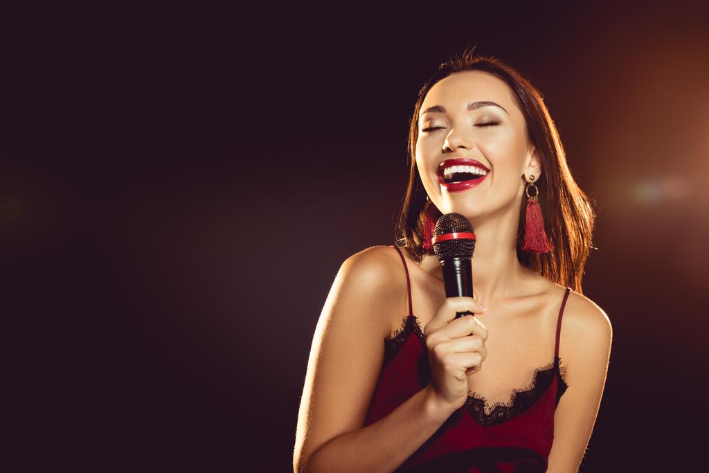 portrait of seductive woman with microphone in hand singing karaoke  - Photo, Image