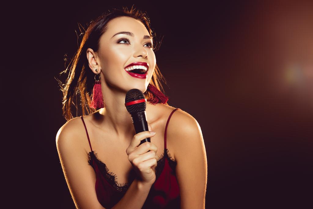 Portret van gelukkige jonge vrouw met microfoon in de hand zingen karaoke  - Foto, afbeelding