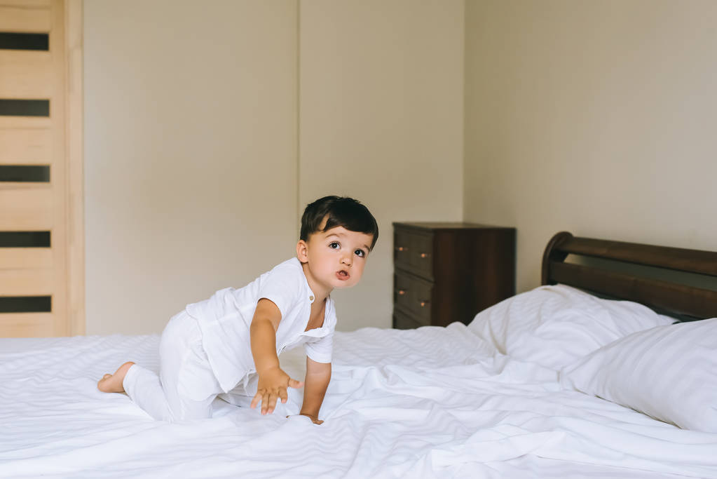 urocze małe dziecko w białe ubrania na łóżku - Zdjęcie, obraz