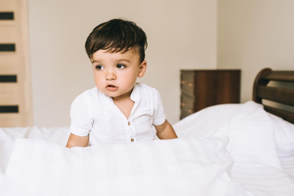 szczegół portret urocze małe dziecko siedzi na łóżku - Zdjęcie, obraz