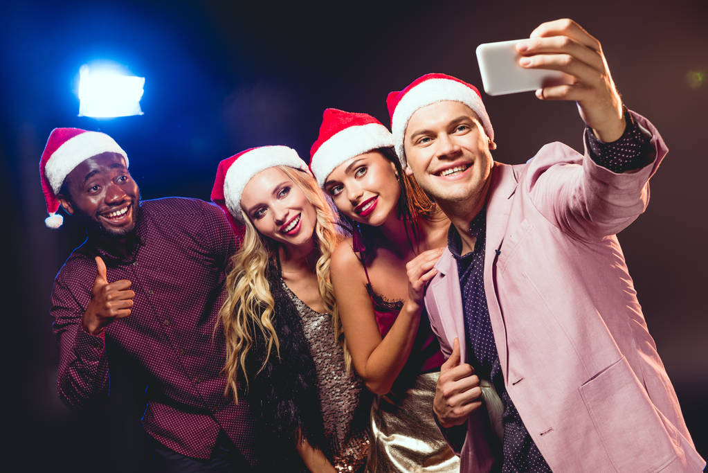 glamourosos amigos multiculturais em chapéus de santa tirar selfie no smartphone
 - Foto, Imagem