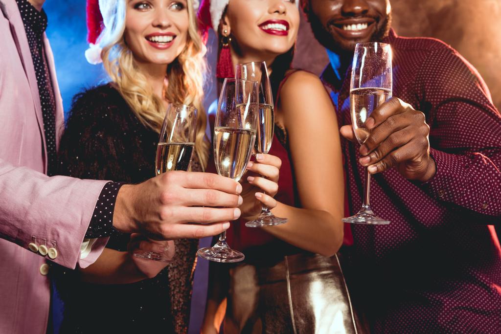 мультиетнічні друзі в капелюхах Санти смердить келихами шампанського на новорічній вечірці
 - Фото, зображення