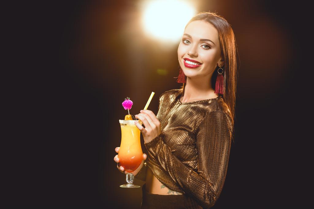 Gelukkig glamoureuze meisje met cocktail op zwart met achtergrondverlichting - Foto, afbeelding