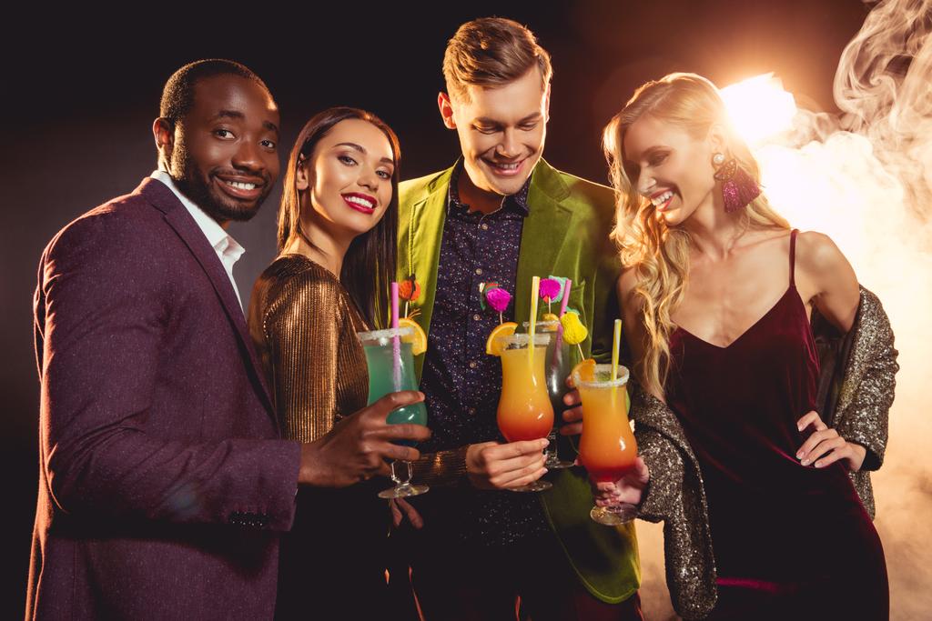 красивые улыбающиеся мультикультурные друзья, держащие коктейли на вечеринке
 - Фото, изображение