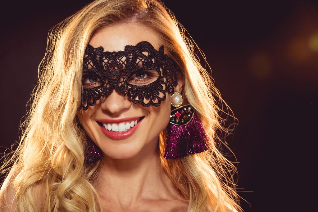 schöne blonde lächelnde Mädchen in schwarzer Karnevalsmaske - Foto, Bild