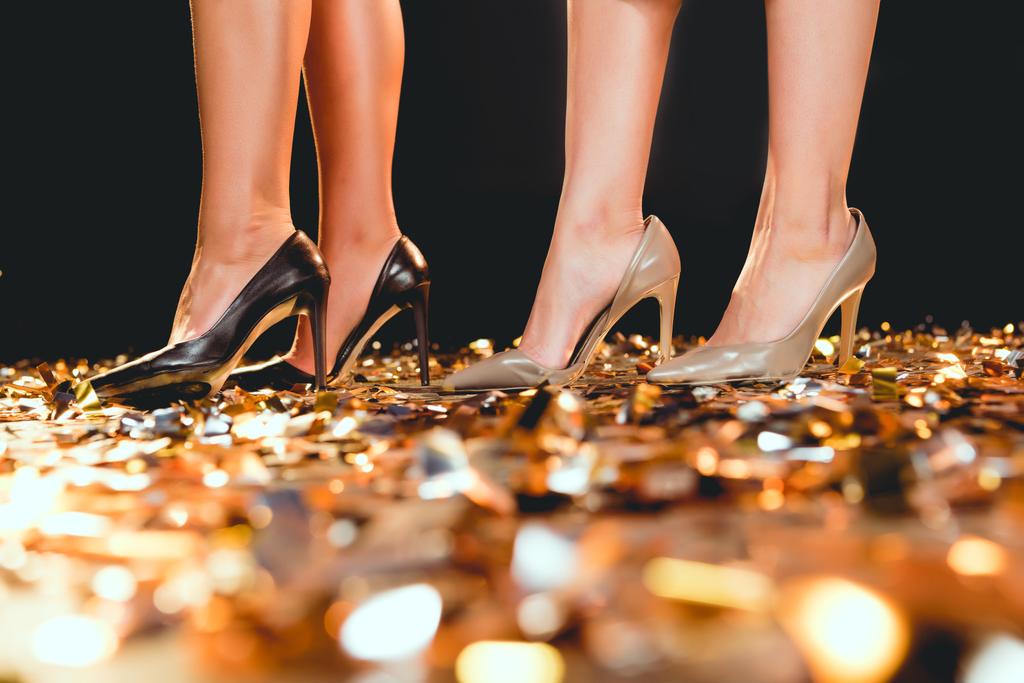 обрезанный вид девушек на высоких каблуках, стоящих на золотых конфетти на вечеринке
 - Фото, изображение