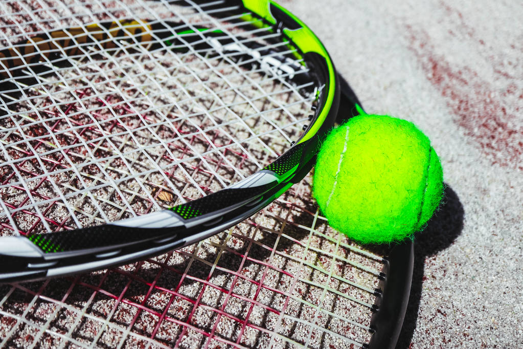 Ρακέτα του τένις και μια μπάλα σε άμμο τένις δικαστήριο παρασκήνιο, κοντινό πλάνο. - Φωτογραφία, εικόνα