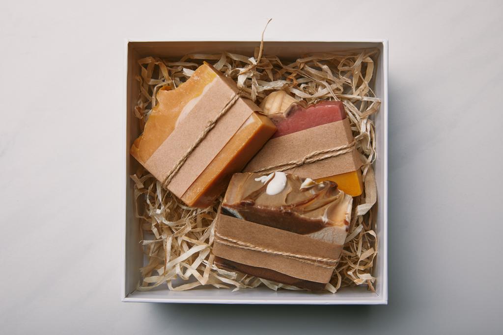 bovenaanzicht van doos met soap binnen op witte marmeren tafelblad - Foto, afbeelding