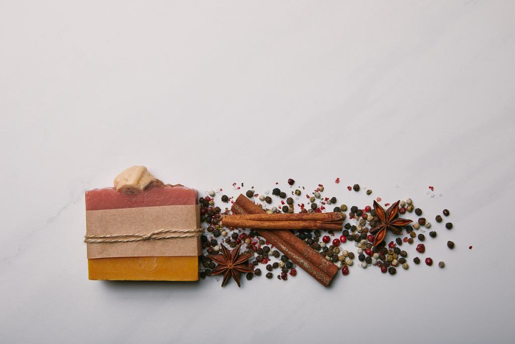 top view of handmade soap with anise, coffee beans and cinnamon sticks on white marble surface - Photo, Image