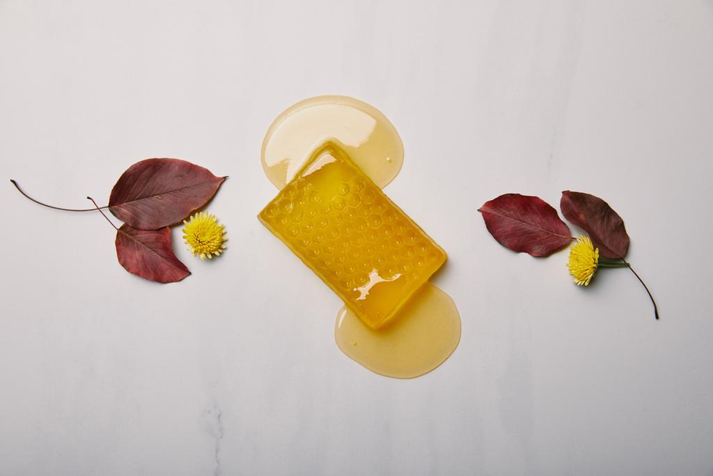 vista superior de jabón de miel con dientes de león y hojas en la superficie de mármol blanco
 - Foto, Imagen