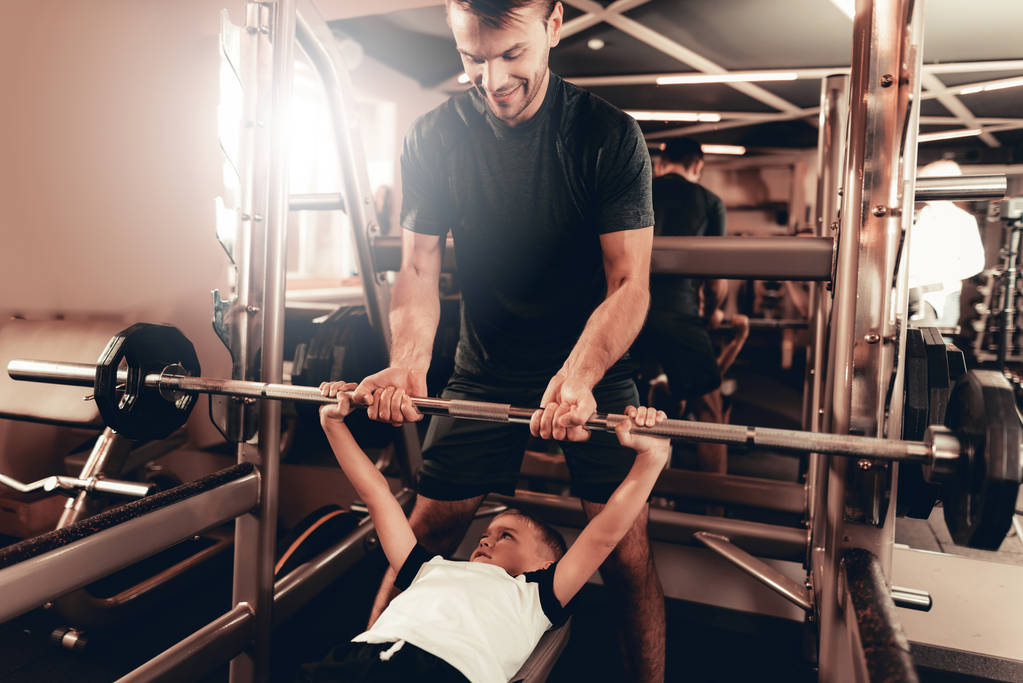 Father Support To Son While Lifting The Barbell. Parenthood Relationship. Sporty Family Concept. Active Lifestyle. Triceps Exercise. Holiday Leisure. Working Out Together. Fitness Day. - Photo, Image