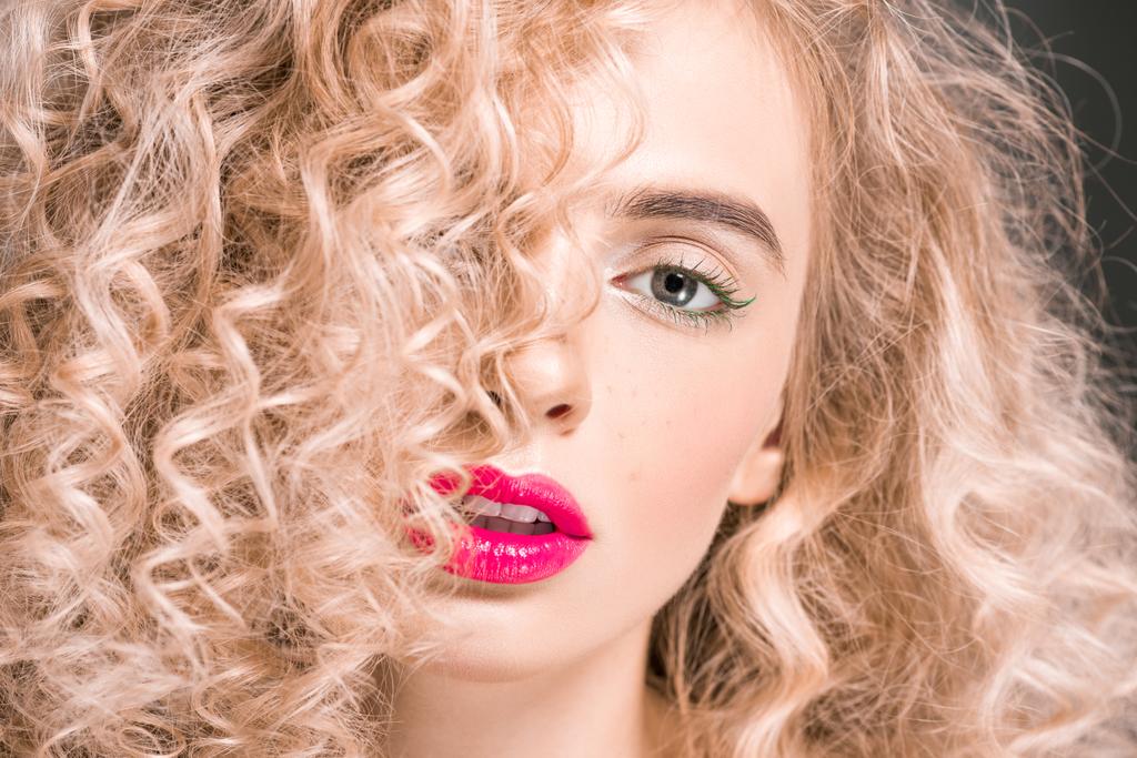 attractive girl with long curly hair looking at camera on grey - Photo, Image