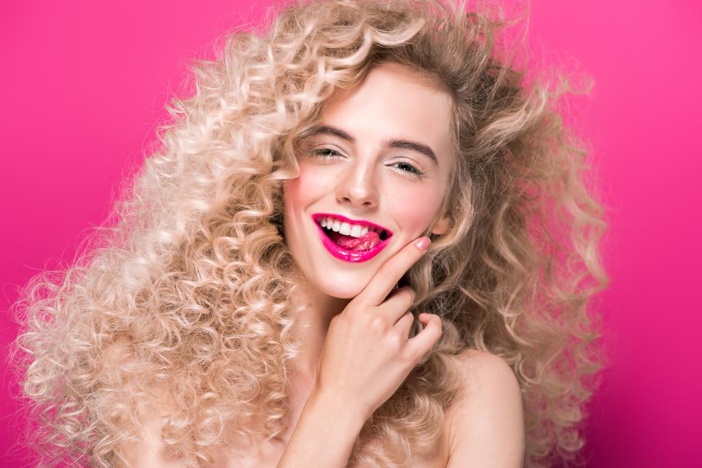 hosszú göndör haja fényképezőgép pink elszigetelt mosolyogva a gyönyörű fiatal nő portréja - Fotó, kép