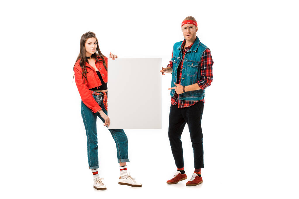 junger männlicher Hipster zeigt auf leeres Banner, während seine Freundin in der Nähe isoliert auf weißem Grund steht - Foto, Bild