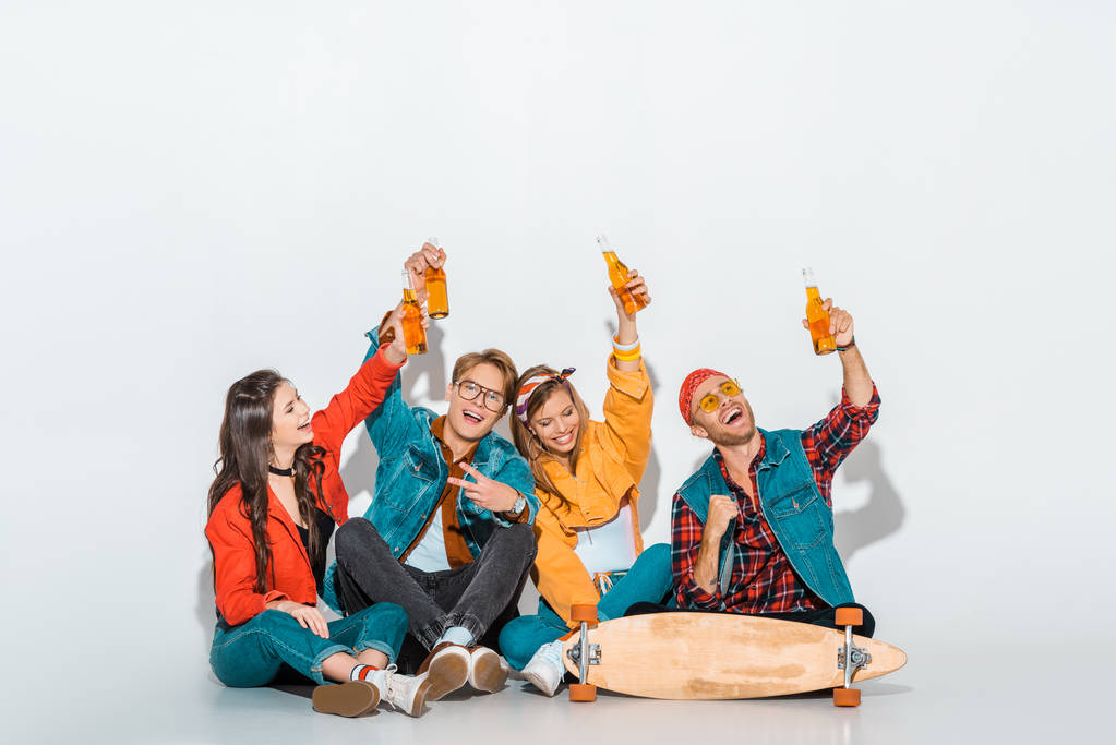 веселі стильні хіпстери сидять зі скейтбордом і тримають пляшки пива
 - Фото, зображення