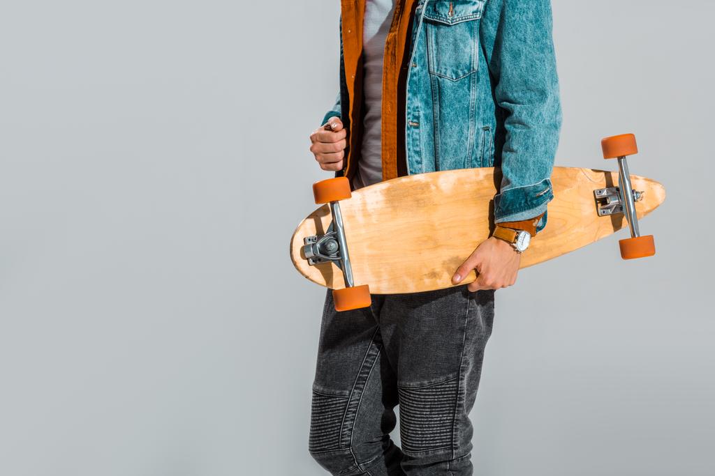 vista cortada de skate elegante segurando longboard isolado em cinza
 - Foto, Imagem