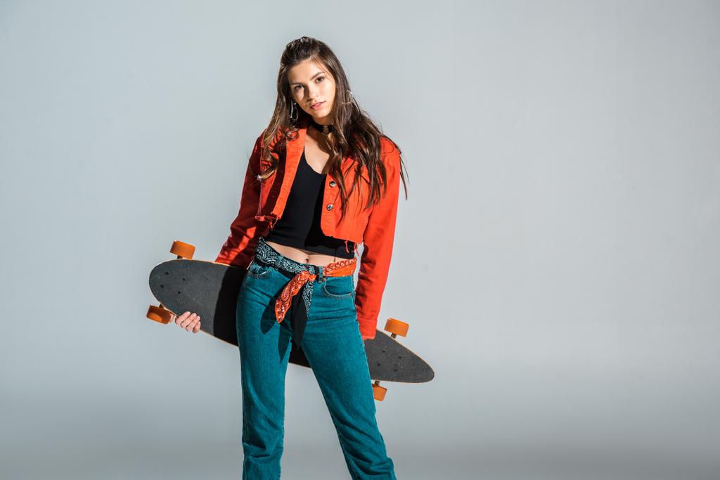 young beautiful woman posing with longboard isolated on grey  - Photo, Image