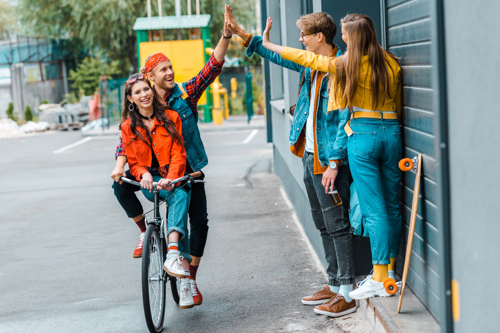 stylowy para jazdy rower i dając highfive do znajomych na ulicy - Zdjęcie, obraz
