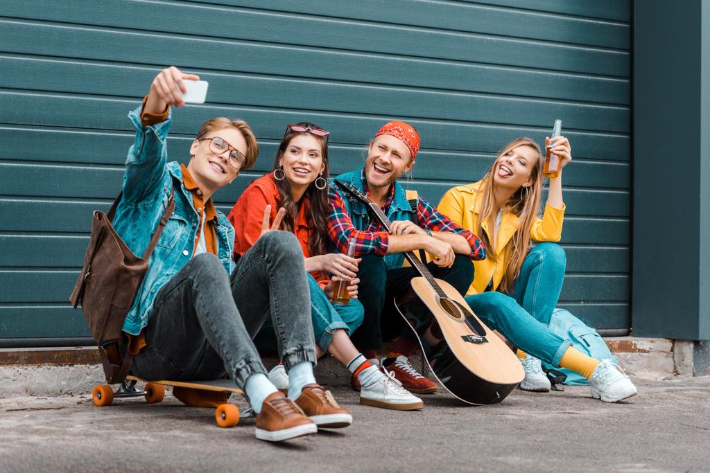 mladí přátelé piva, skateboard a kytara s selfie na smartphone - Fotografie, Obrázek