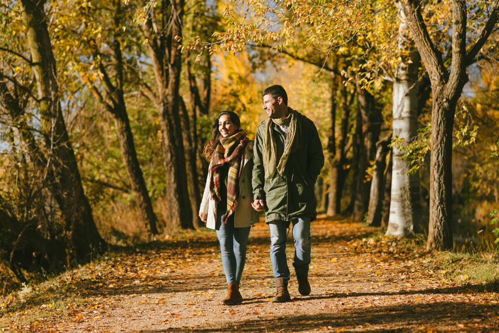 Jeune couple marchant ensemble en plein air en automne. Deux amoureux profitant des loisirs de la saison d'automne dans la nature
. - Photo, image
