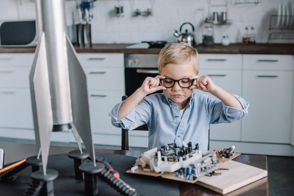 adorable boy touching glasses and looking at circuit board in kitchen on weekend - Photo, Image