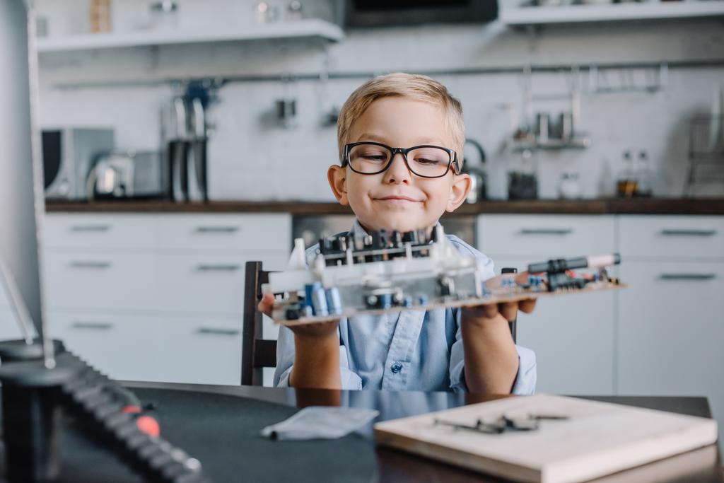 adorable boy holding motherboard at table at home - Photo, Image