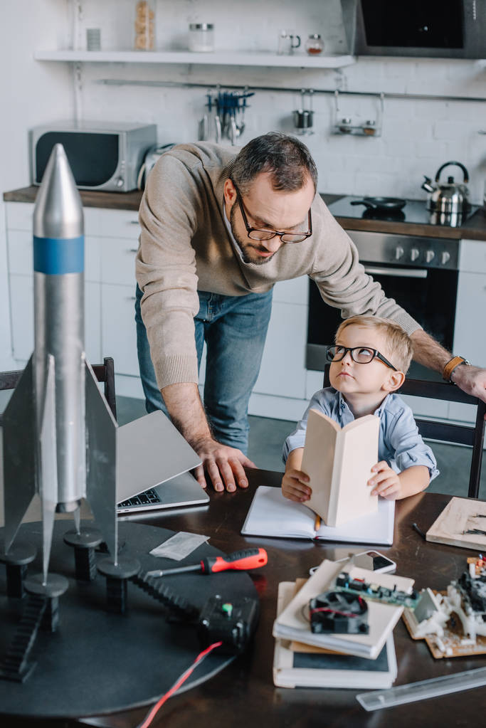 Vater und Sohn modellieren Rakete und sehen sich zu Hause an - Foto, Bild
