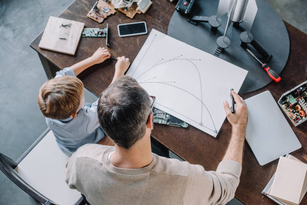 Vater und Sohn betrachten Bauplan für Modellierrakete zu Hause - Foto, Bild