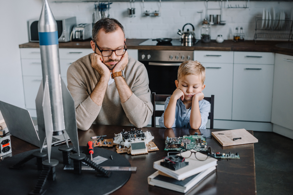 pensive father and son looking at circuit board on table at home - Photo, Image
