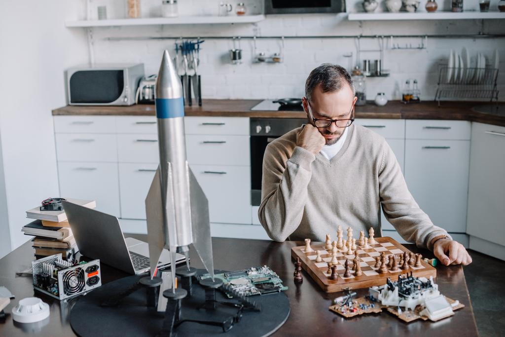 homem bonito pensativo olhando para tabuleiro de xadrez em casa
 - Foto, Imagem