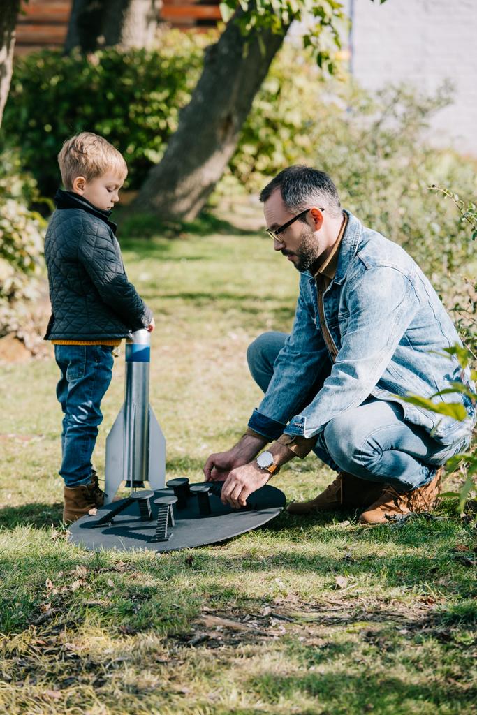 boční pohled na otce a malý syn zahajuje model rakety venkovní - Fotografie, Obrázek