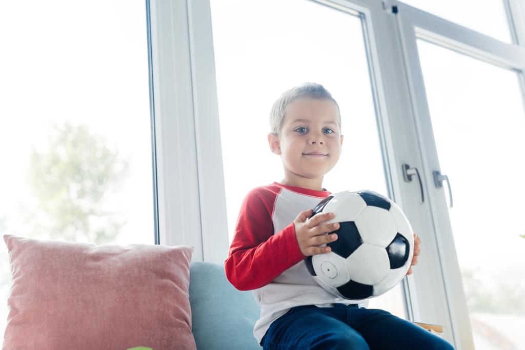 portrét s fotbalovým míčem v rukou doma roztomilé dítě - Fotografie, Obrázek