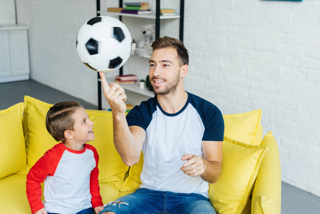 πορτρέτο του πατέρα και γιο με μπάλα ποδοσφαίρου στο σπίτι - Φωτογραφία, εικόνα