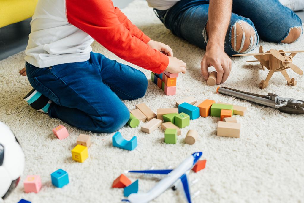 visão parcial de pai e filho brincando com blocos de madeira juntos em casa
 - Foto, Imagem