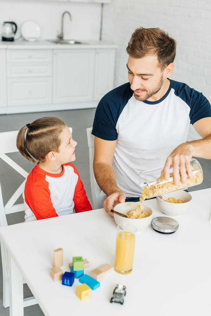 щасливий батько і маленький син снідають разом на кухні вдома
 - Фото, зображення