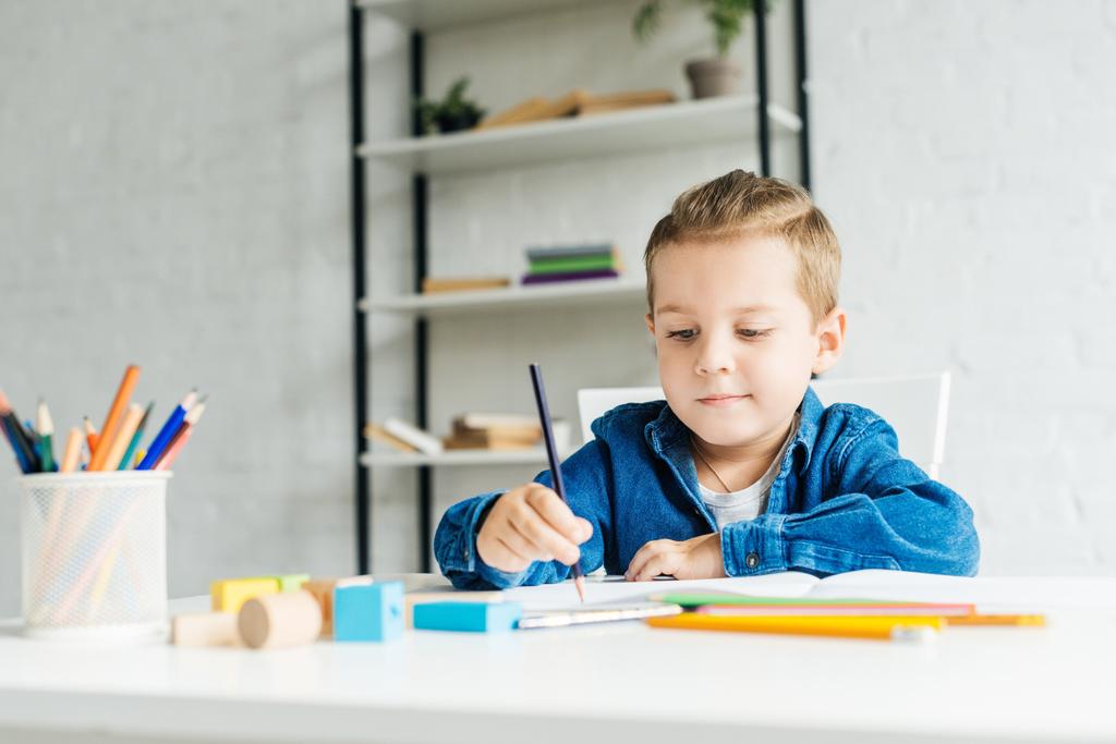 petit dessin d'enfant concentré avec crayons de couleur à la maison
 - Photo, image