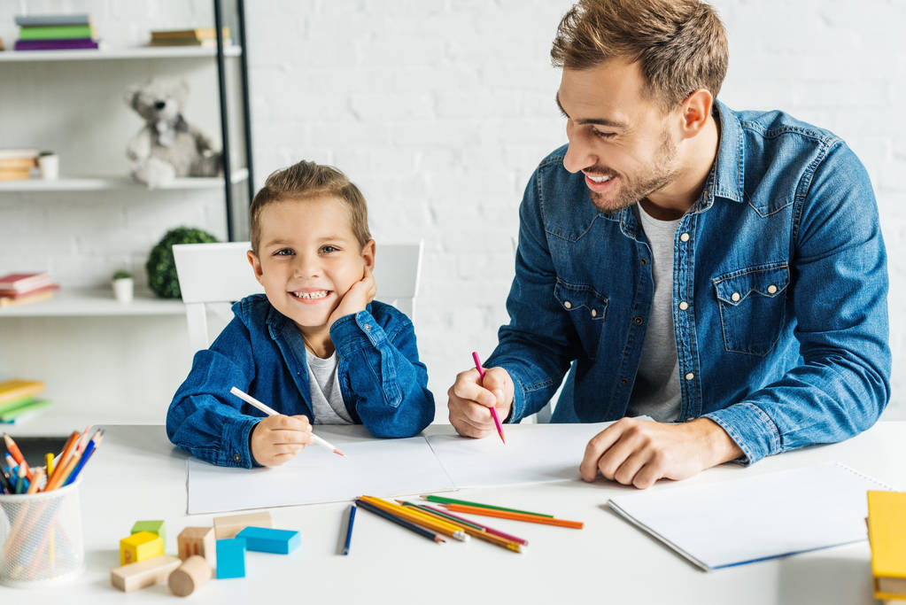 красивый молодой отец рисует с улыбающимся маленьким сыном дома
 - Фото, изображение