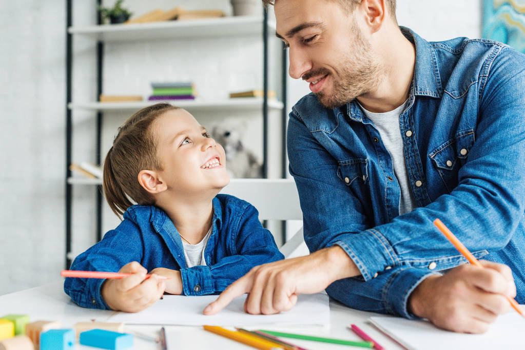 sonriente joven padre dibujo con hijo en casa
 - Foto, Imagen