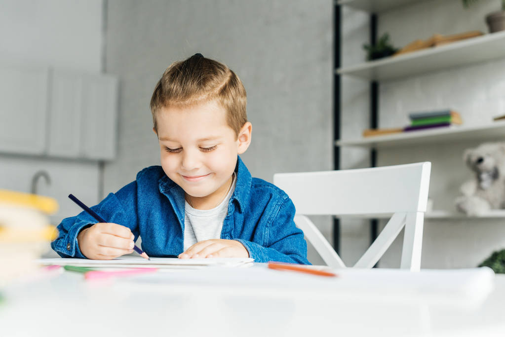 lachende kindje tekenen met kleur potloden thuis - Foto, afbeelding