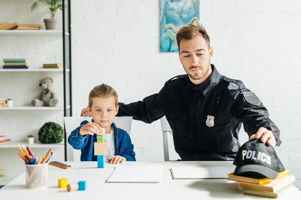 красивый молодой отец в полицейской форме и сын играют вместе дома
 - Фото, изображение