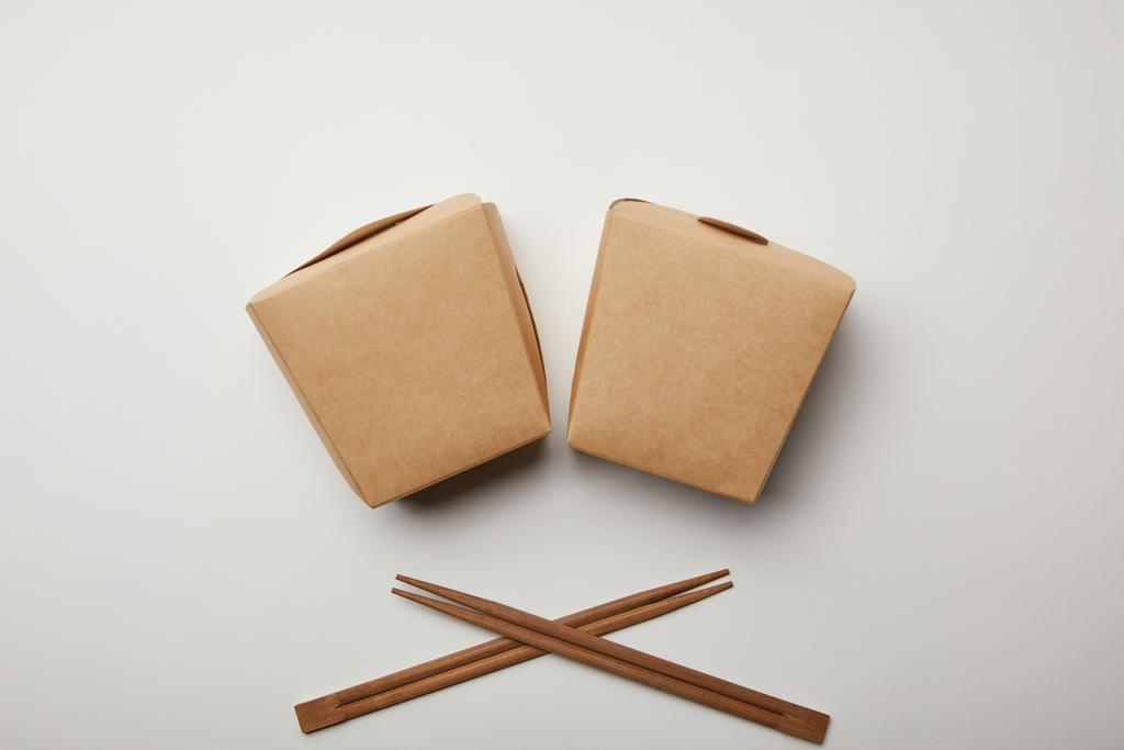 Draufsicht auf arrangierte Wok-Boxen und Essstäbchen auf weißer Oberfläche, minimalistisches Konzept  - Foto, Bild
