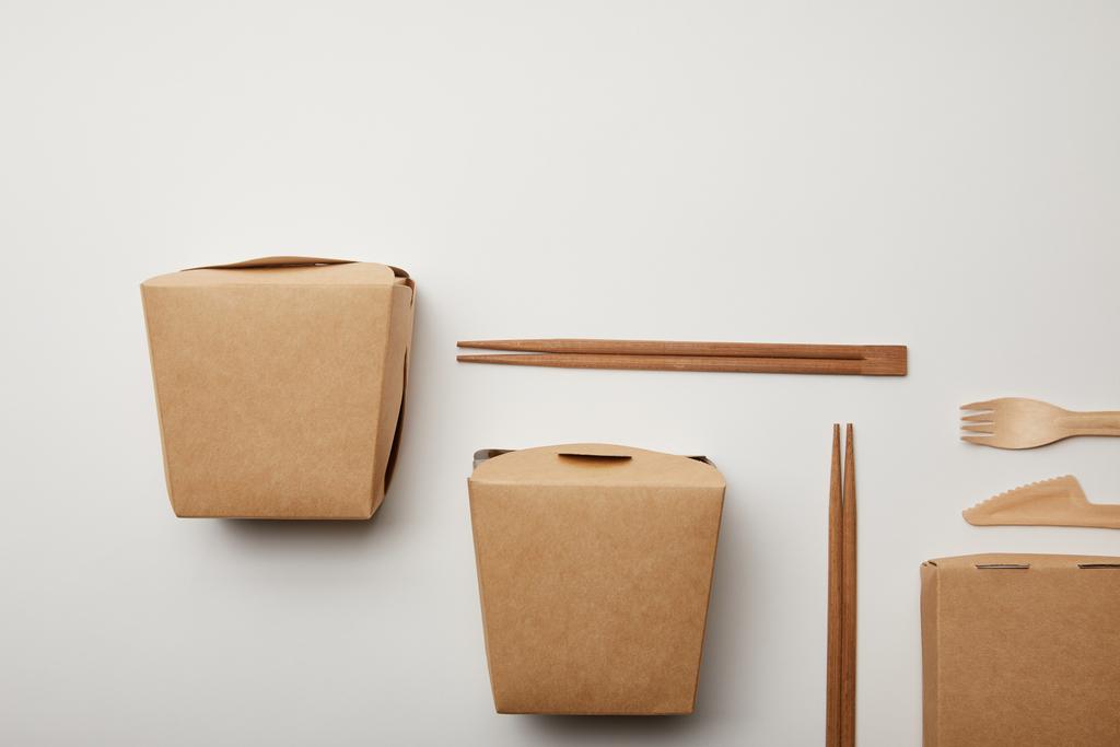 vista sopraelevata di scatole wok disposte, bacchette e coltello usa e getta con forchetta sulla superficie bianca
 - Foto, immagini