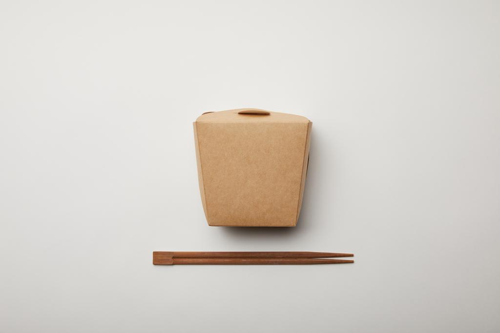 verhoogde weergave van gearrangeerde stokjes en noodle box op witte ondergrond, minimalistische concept  - Foto, afbeelding